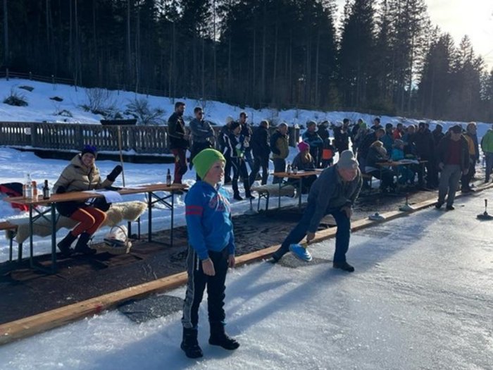 Lattlschießen der Handwerker/innen erfreut sich größter Beliebtheit Menschen spielen Eisstockschießen auf zugefrorenem Gewässer im Winter