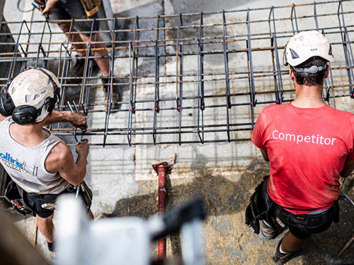 Die temporäre Unterkunft ist eine betriebliche Notwendigkeit Zwei Bauarbeiter mit Helmen montieren Stahlarmierung auf einer Baustelle