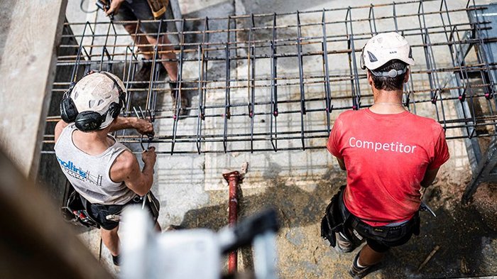 Die temporäre Unterkunft ist eine betriebliche Notwendigkeit Zwei Bauarbeiter mit Helmen montieren Stahlarmierung auf einer Baustelle