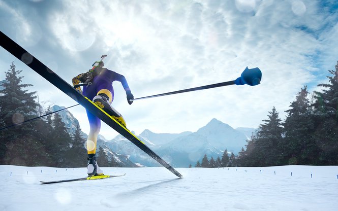 Home Sciatore di fondo con abbigliamento giallo e blu su pista innevata con montagne sullo sfondo