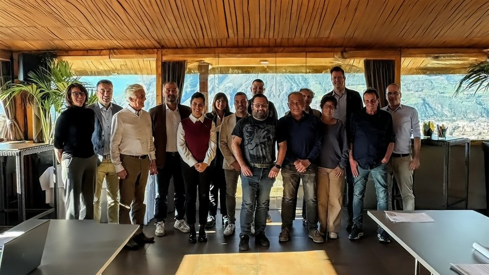 Foto di gruppo di 15 persone in una stanza con vista sulle montagne