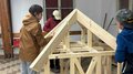 JHW-Wipptal Drei Kinder bauen ein Gerüst aus Holz für ein kleines Haus im Innenraum