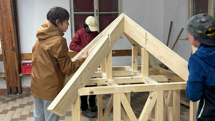 JHW-Wipptal Drei Kinder bauen ein Gerüst aus Holz für ein kleines Haus im Innenraum
