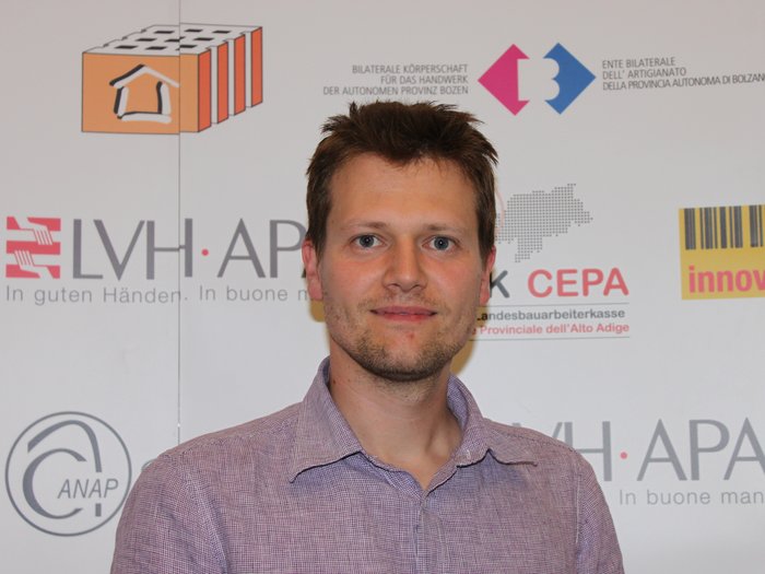 Revisionen aufgeschoben, frühzeitiger Termin dennoch wichtig Porträt eines Mannes vor einer Wand mit Logos und Texten in Deutsch und Italienisch