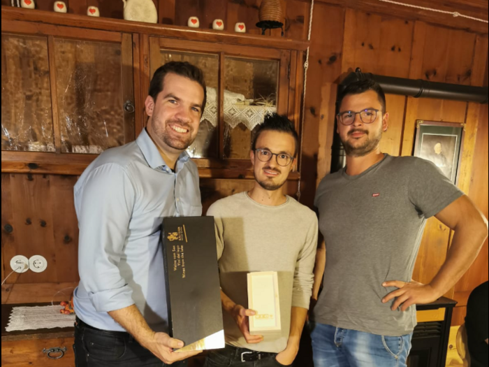 © WKO Tirol Drei Männer stehen in einem Holzraum, zwei halten Geschenkboxen