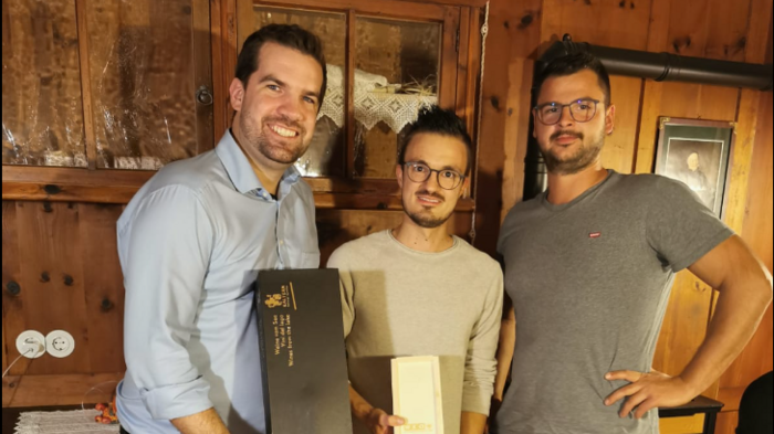 © WKO Tirol Drei Männer stehen in einem Holzraum, zwei halten Geschenkboxen