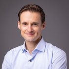 Drucker und Mediengestalter Porträt eines lächelnden Mannes in hellblauem Hemd vor grauem Hintergrund