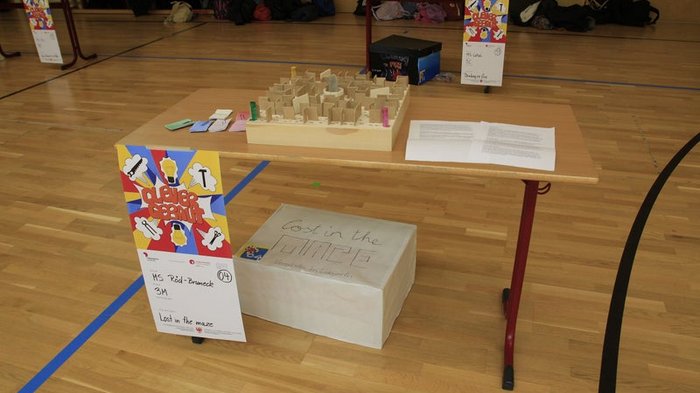 Kreative Spielideen: Preisverleihung für "Clever gebaut" Ein Holzlabor mit einem Labyrinth und Papier auf einem Tisch in einer Turnhalle.
