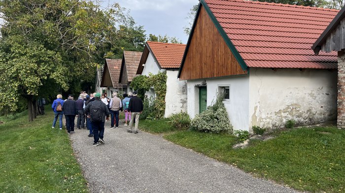 Althandwerker/innen unterwegs: Rundfahrt Weinviertel Gruppe von Menschen auf einem Weg neben kleinen Häusern mit roten Dächern
