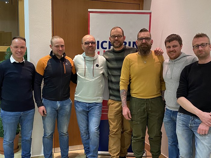 lvh Lajen: Nachwuchsförderung im Mittelpunkt Sieben Männer stehen vor einer Tür und einem Banner in Innenraum