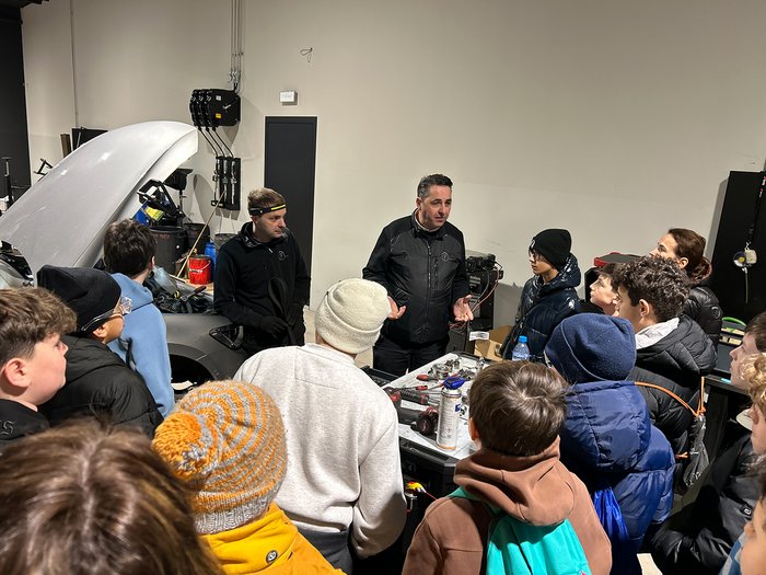 Handwerks- und Gastbetriebe im Fokus Gruppe von Jugendlichen hört einer Erklärung in einer Autowerkstatt zu