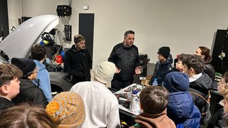 News Gruppe von Jugendlichen hört einer Erklärung in einer Autowerkstatt zu