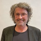 Pittori e verniciatori Uomo con occhiali, capelli ricci grigi e barba sorride amichevolmente