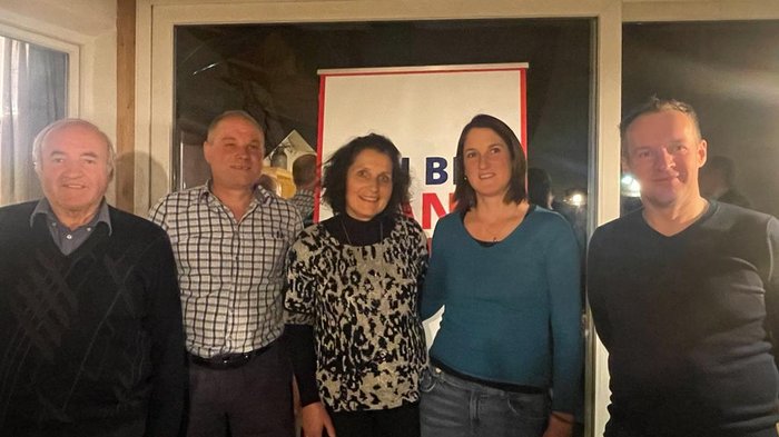 Wir sind Handwerk! Fünf Menschen stehen vor einem Fenster mit einem Plakat im Hintergrund
