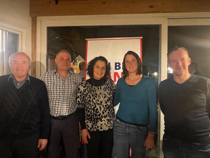 Wir sind Handwerk! Fünf Menschen stehen vor einem Fenster mit einem Plakat im Hintergrund