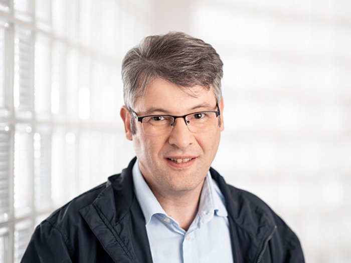 KOBRA: Kurt Egger übergibt nach 22 Jahren das Amt an Klaus Nagler Porträt eines Mannes mit Brille vor Glassteinwand