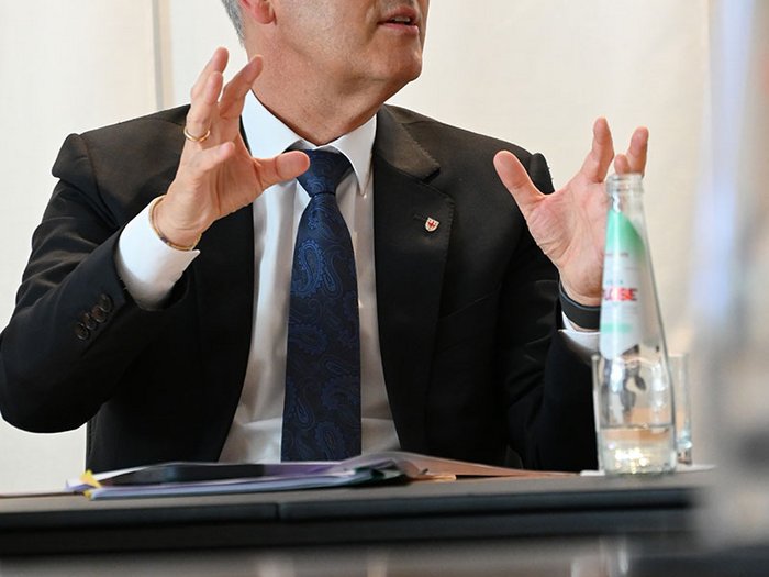 Wohnen muss leistbar sein! Herausforderungen und Lösungsansätze in Südtirol Mann im Anzug spricht gestikulierend während eines Treffens