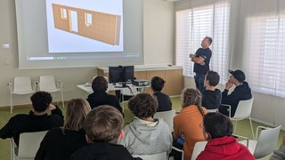 News Lehrer erklärt Architekturmodell vor Schülern in einem Klassenzimmer
