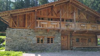 News Rustikales Haus mit Stein- und Holzwänden in bewaldeter Bergumgebung