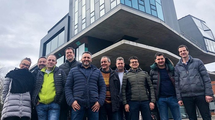 Digitalisierung, das moderne Werkzeug Gruppe von zehn Personen vor modernem Bürogebäude bei bewölktem Himmel