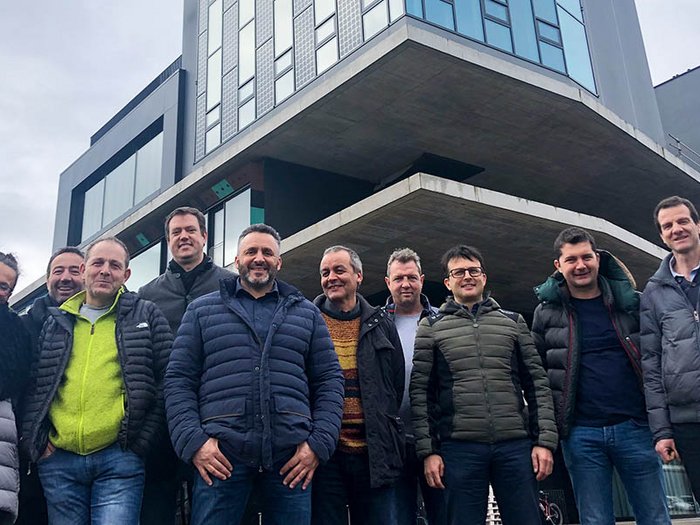 Digitalisierung, das moderne Werkzeug Gruppe von zehn Personen vor modernem Bürogebäude bei bewölktem Himmel