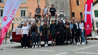 News Gruppe von Menschen vor historischem Uhrturm auf gepflastertem Platz