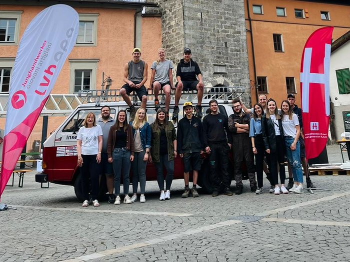 Un laboratorio interattivo in Alta Val d‘Isarco Gruppo di persone davanti a una torre campanaria storica in piazza lastricata