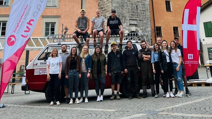 11 Handwerksbetriebe verwandeln Sterzing in eine interaktive Werkstatt Gruppe von Menschen vor historischem Uhrturm auf gepflastertem Platz