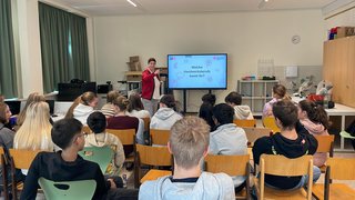 News Lehrerin stellt Schülern in einem Klassenzimmer Handwerksberufe vor