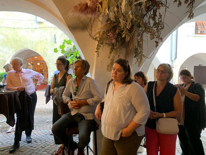 © Plattform Land Menschen stehen und hören unter einem Bogen mit Trockenblumen zu