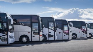 News Reihe geparkter weißer Reisebusse unter blauem Himmel mit Wolken
