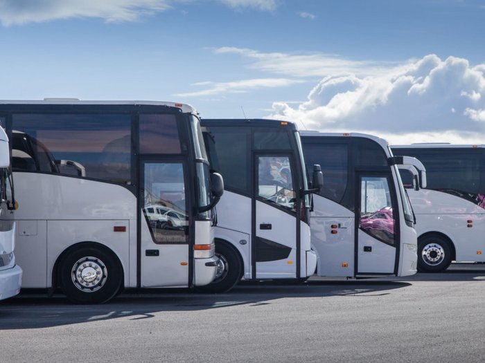 Südtirols Busse stehen still – 100 Prozent Ausfall aufgrund des Coronavirus Reihe geparkter weißer Reisebusse unter blauem Himmel mit Wolken