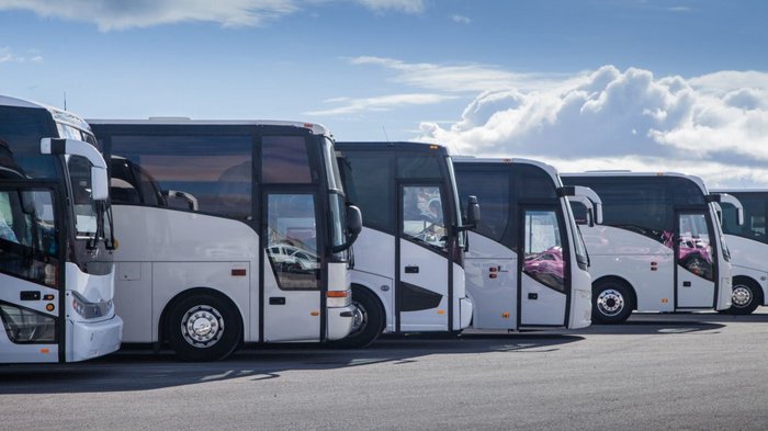 Südtirols Busse stehen still – 100 Prozent Ausfall aufgrund des Coronavirus Reihe geparkter weißer Reisebusse unter blauem Himmel mit Wolken