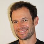 Kaminkehrer Nahaufnahme eines lächelnden Mannes mit leichtem Bart und dunklem T-Shirt vor weißem Hintergrund