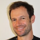 Kaminkehrer Nahaufnahme eines lächelnden Mannes mit leichtem Bart und dunklem T-Shirt vor weißem Hintergrund