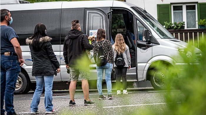 Personentransport: Gesetzlichen Spielraum nutzen und Südtiroler Betrieben aus der Krise helfen! Menschen stehen in einer Schlange, um in einen Kleinbus einzusteigen