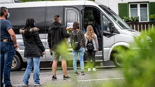 News Menschen stehen in einer Schlange, um in einen Kleinbus einzusteigen