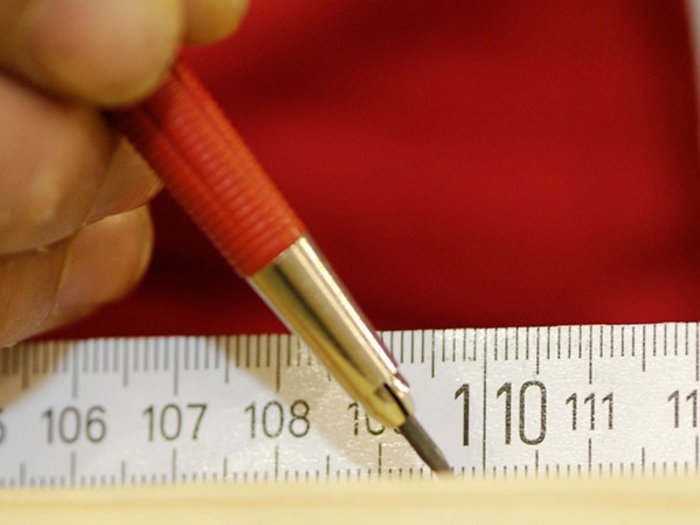 Berufsbildender Bachelor in Holzingenieurwesen vorgestellt Hand zeichnet mit rotem Bleistift auf Maßband bei 110 cm