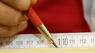 News Hand zeichnet mit rotem Bleistift auf Maßband bei 110 cm