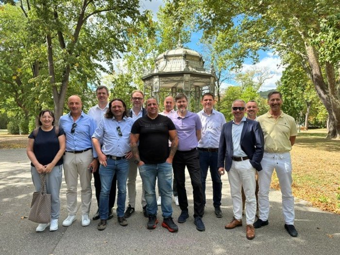 Elektrohandwerk im Wandel Gruppe von Erwachsenen posiert in einem Park vor einem gläsernen Pavillon
