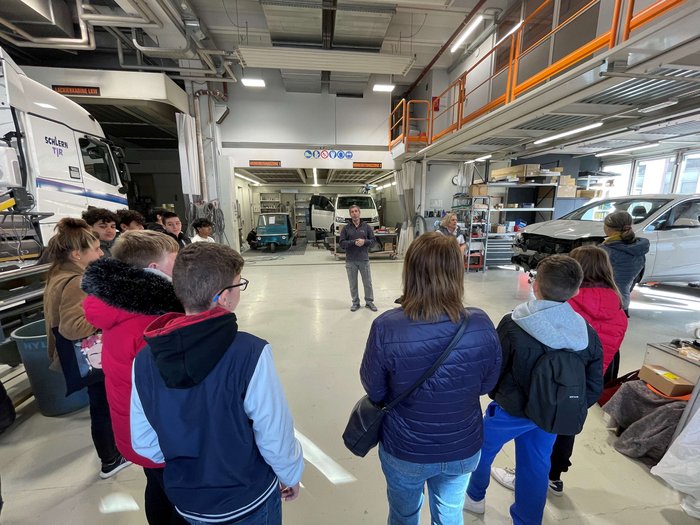 A Bolzano i giovani scoprono le professioni dell'artigianato e dell'ospitalità Gruppo di persone in officina ascolta un uomo durante una presentazione