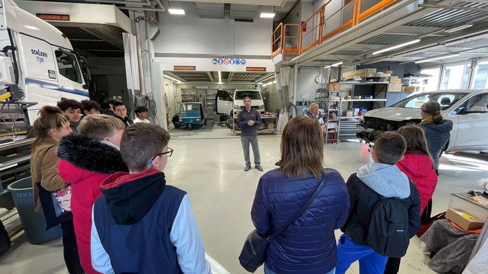 Jugendliche in Bozen entdecken Berufe im Handwerk und Gastgewerbe Gruppe von Menschen hört in Werkstatt einem Mann bei einer Präsentation zu