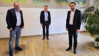 News Drei Männer in einem Raum mit Abstand zueinander