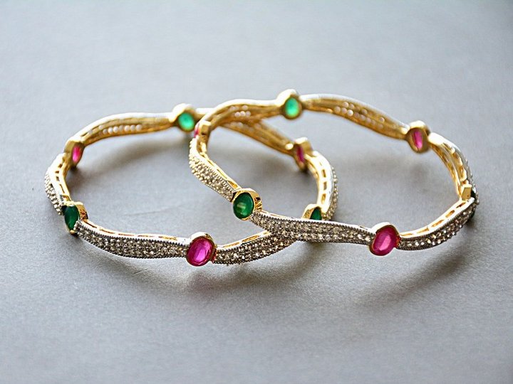 Orafi e argentieri Due braccialetti d'oro con pietre preziose rosse e verdi su sfondo grigio