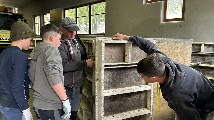 Deutschsprachiges WorldSkills-Ländertreffen in Südtirol Mehrere Personen inspizieren eine große Betonform in einer Werkstatt