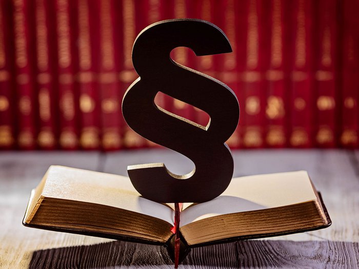 Il nuovo registro dei rifiuti Simbolo del paragrafo su libro aperto davanti a scaffale di libri rossi