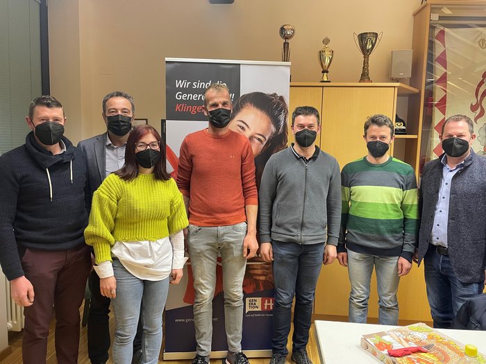 Vöraner Handwerk hat viel vor Sieben Personen mit schwarzen Masken stehen in einem Raum vor einem Banner und einem Schrank mit Pokalen