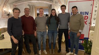 News Sechs Personen stehen in einem Raum mit bemalter Decke und Leseplakat im Hintergrund