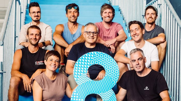 Rittner Musterschau: Der Ritten wird zur Bühne für Wirtschaft und Ideen Gruppe von neun Personen sitzt auf blauen Treppen, hält große blaue Zahl 8