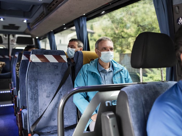 Mietwagenunternehmer: "Die Kapazitäten wären vorhanden" Menschen mit Schutzmasken sitzen in einem Bus mit sozialen Distanzmaßnahmen